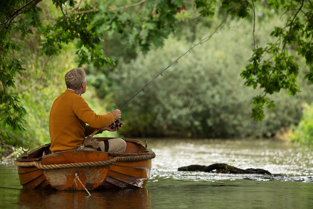 Man fly fishing from boat on river