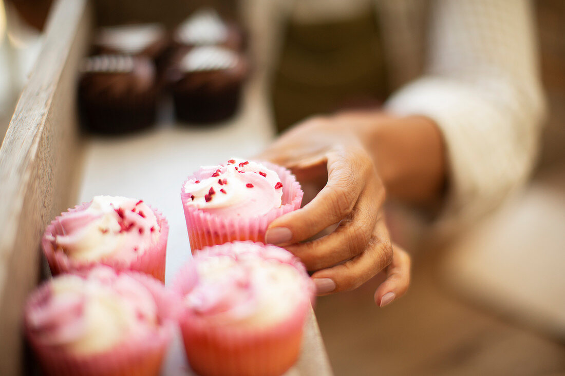 Hand reaching for pink cupcake