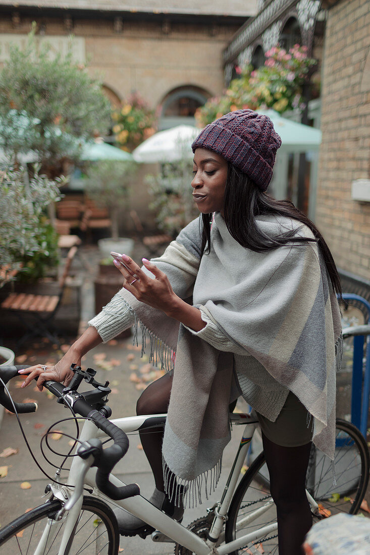 Young woman with smartphone on bicycle