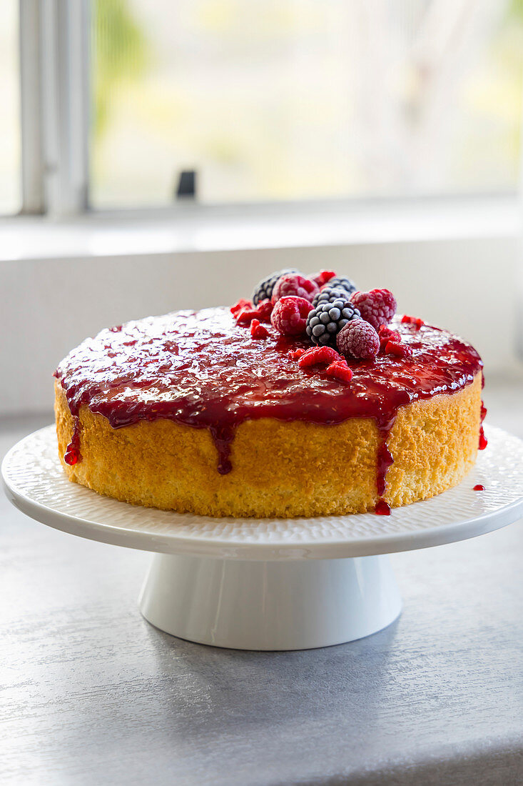 Zitronen-Himbeer-Kuchen auf Tortenständer auf Fensterbrett