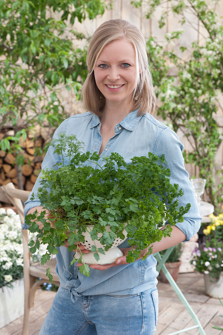 A woman holding a colander planted with parsley