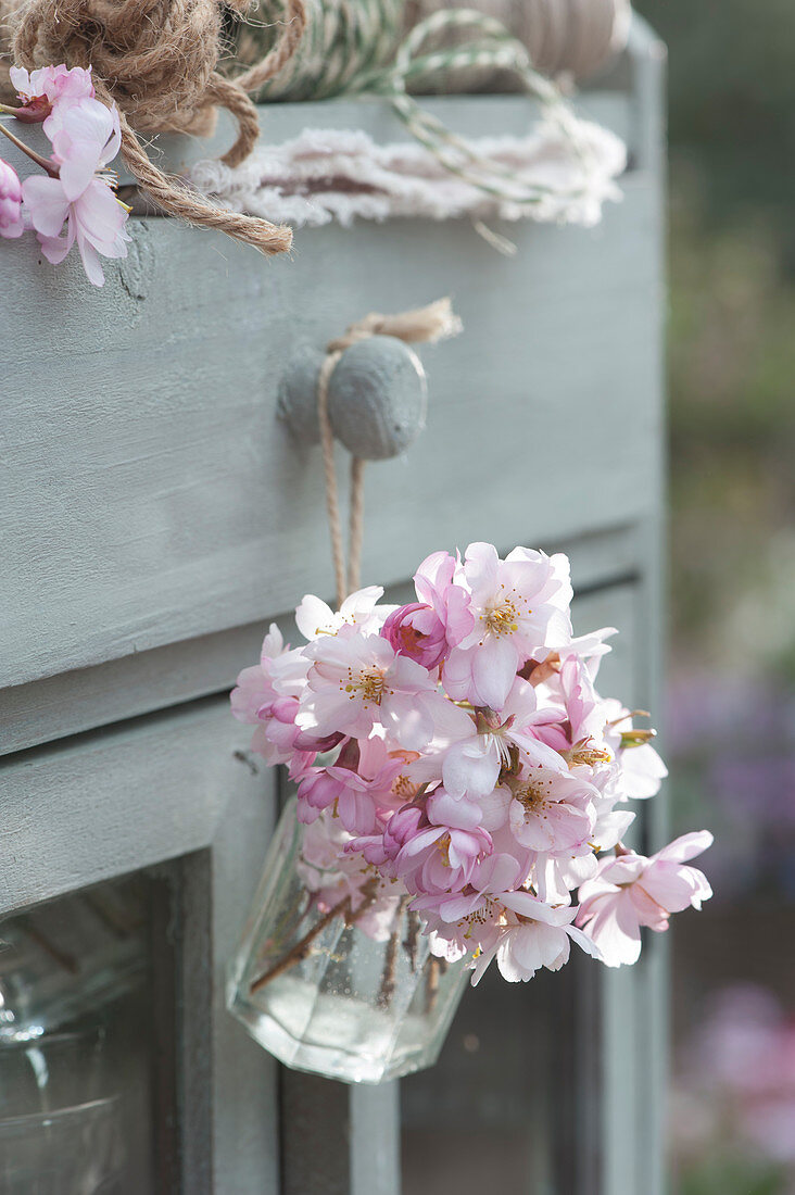 A small bouquet of flowering ornamental cherry hanging from a drawer knob