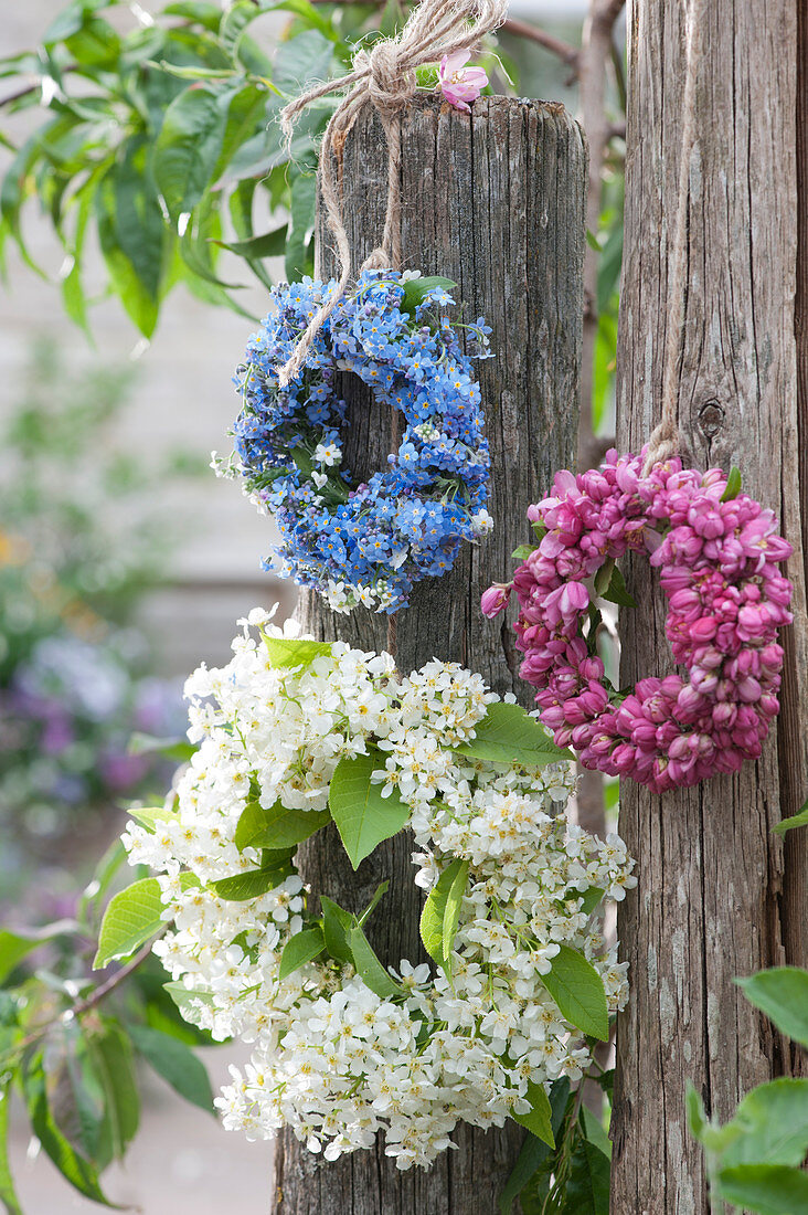 Wreaths of forget-me-nots, crab apple blossoms, and bird cherry hanging from posts