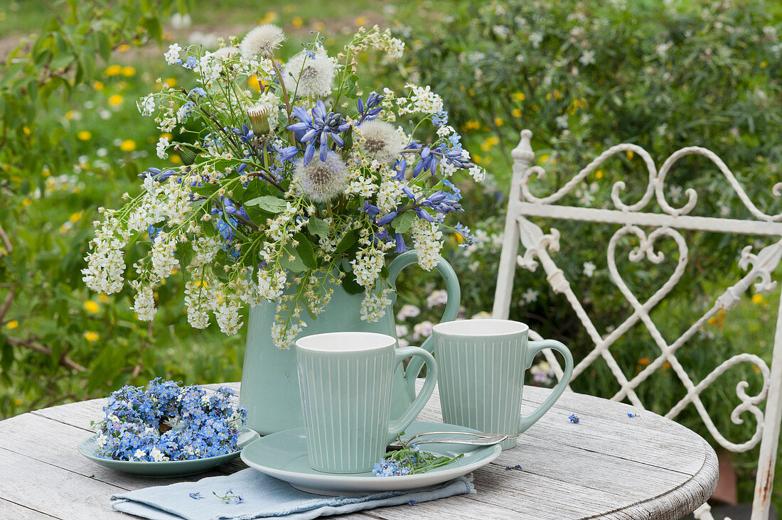 Unusual bouquet with bird cherry, bluebells, and dandelions, a wreath of forget-me-nots