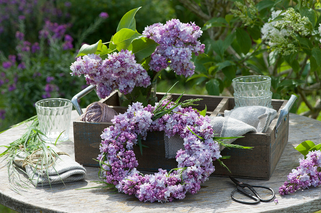 Wreath and bouquet of lilacs on a wooden tray