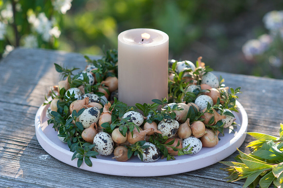 Easter wreath made of boxwood, onions, and quail eggs, with a candle in the middle