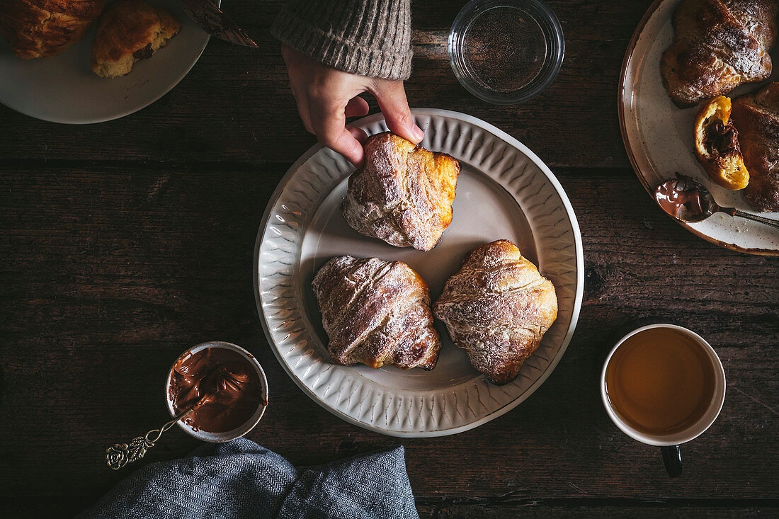 Frühstück mit Croissants, Tee und Schokoladenaufstrich