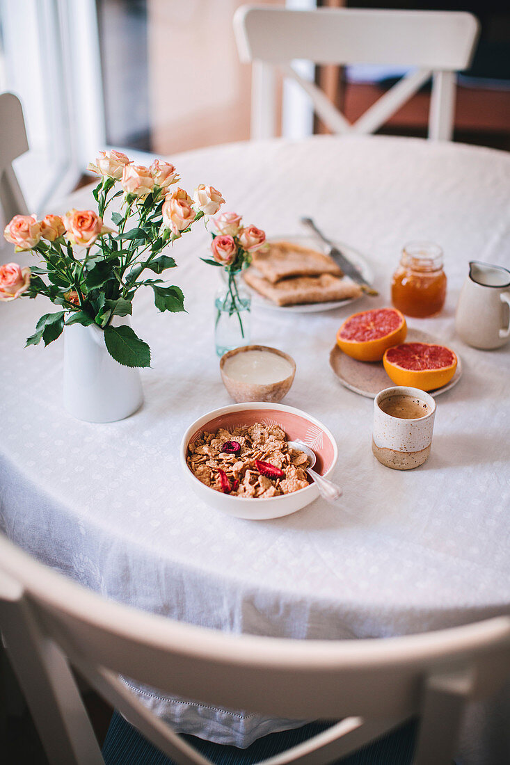 Kaffee, Müsli, Grapefruit und Pfannkuchen auf Frühstückstisch