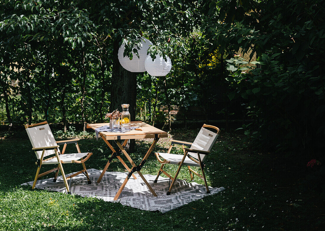 Tisch mit Stühlen auf Teppich im Garten