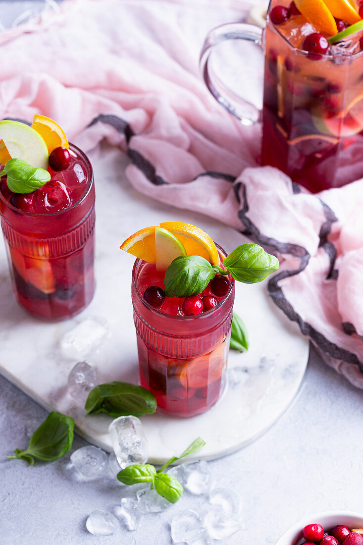 Fruchtcocktail mit Äpfeln, Cranberries, Orangen und Basilikum