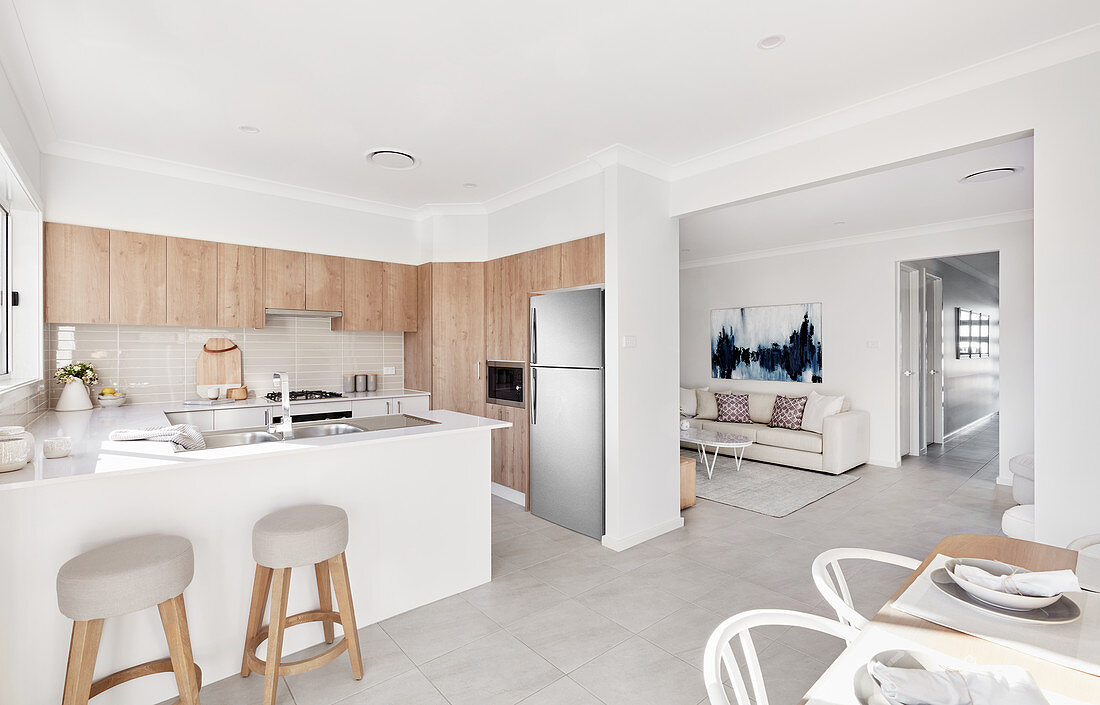 Island counter and bar stools in bright kitchen with dining area in foreground