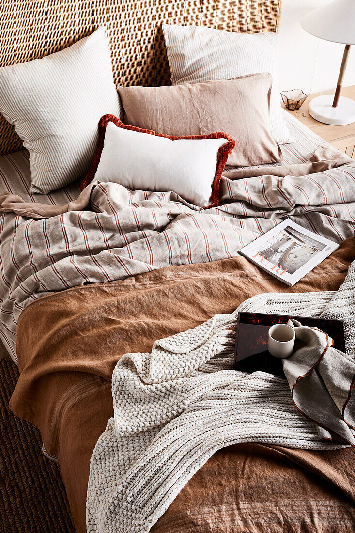 Doppelbett mit Kissen, brauner Tagesdecke und Strickdecke