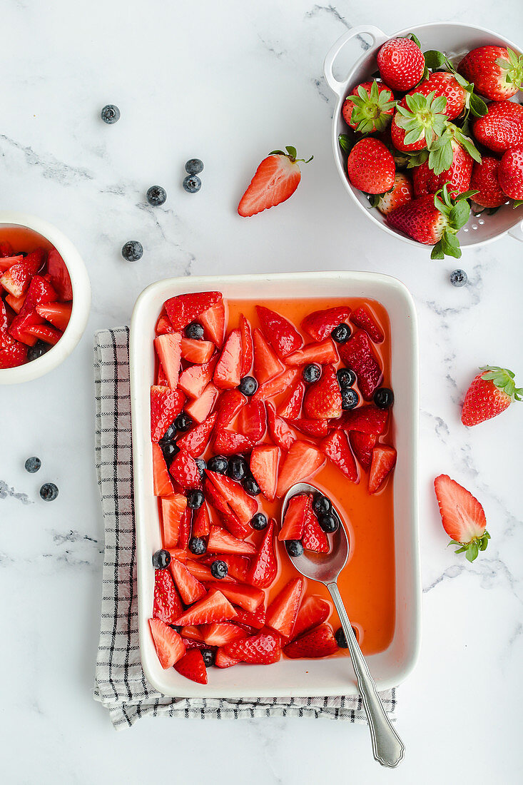 Obstsalat mit Erdbeern, Heidelbeeren, Zitrone und Zucker