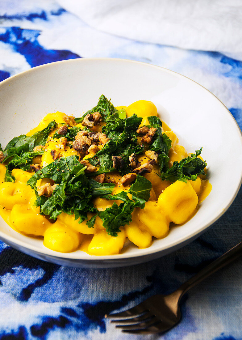 Bowl of gnocchi pasta in a pumpkin sauce with kale and walnuts