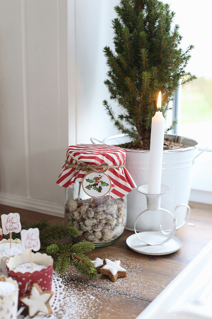 Roasted almonds next to a candle on a worktop decorated for Christmas