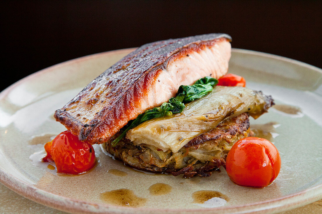 Pan fried salmon steak on potato rosti and spinach with cherry tomatoes