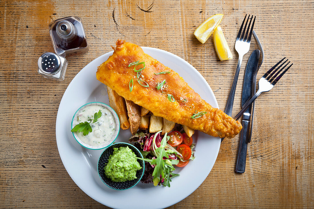 Panierter Fisch auf Kartoffelspalten mit Erbsenpüree und Sauce Tartare