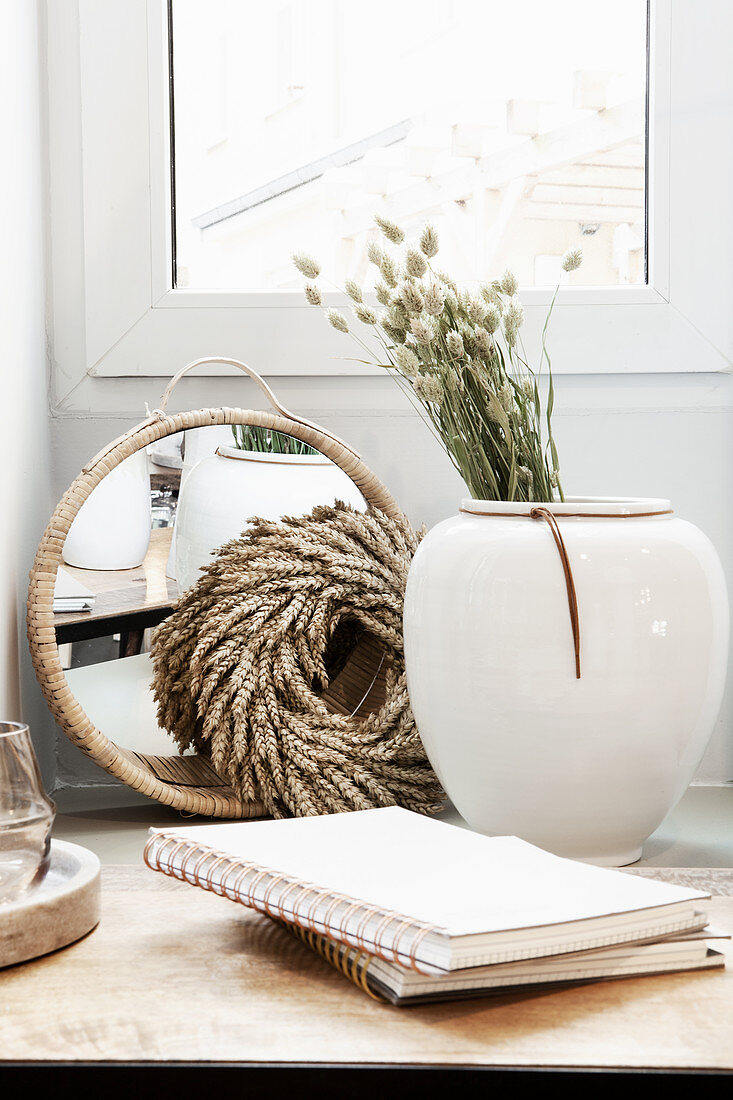 Vase with dried flowers, wreath, mirror and notebooks