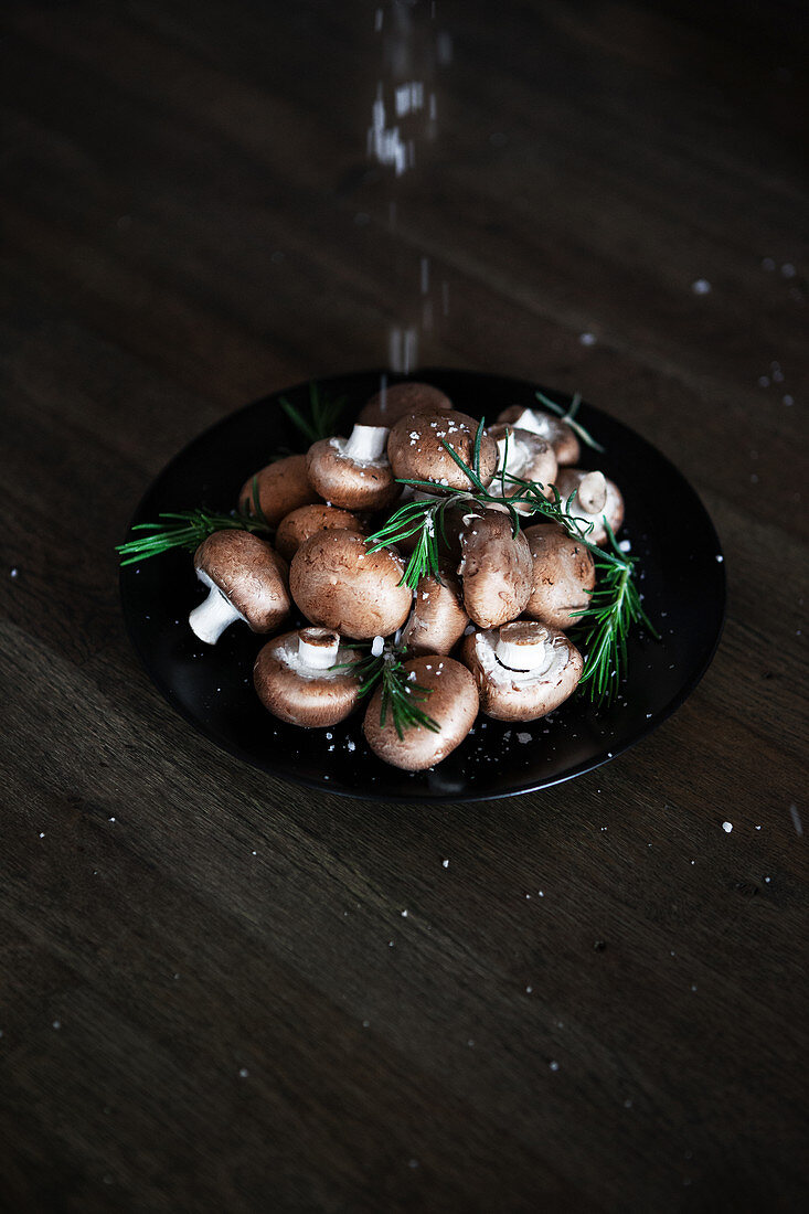 Sea salt and rosemary on button mushrooms in a bowl