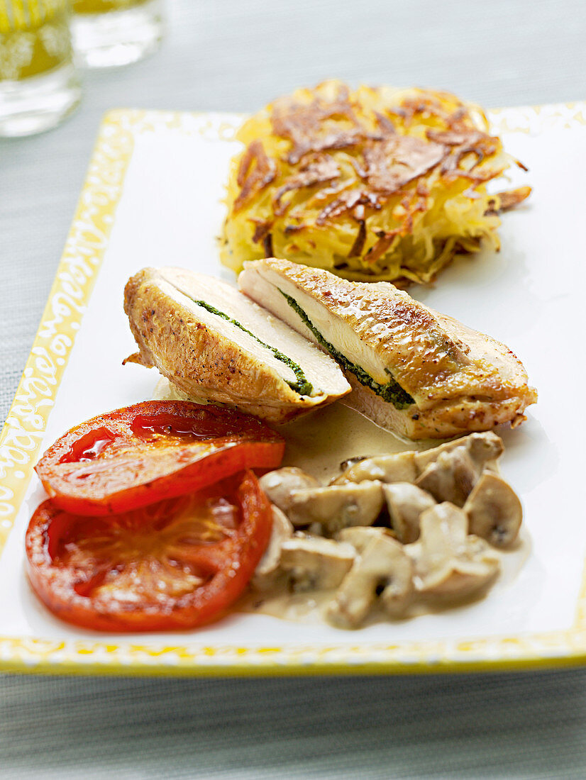 Stuffed chicken breast with grilled tomatoes, latkes and mushrooms in a cream sauce