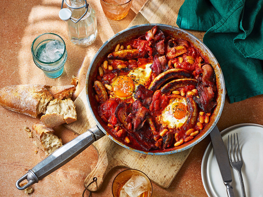 Englisches Frühstück mit Bohnen, Würstchen und Eiern serviert in der Pfanne