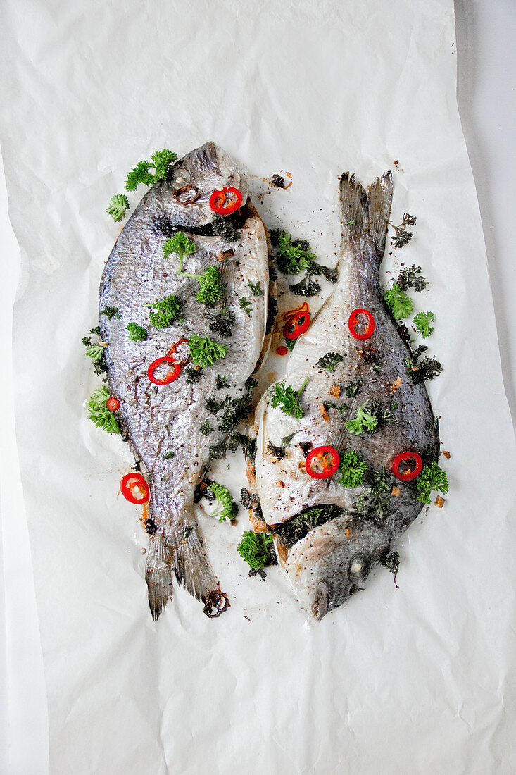 Fresh sea bream with parsley and chilis on paper