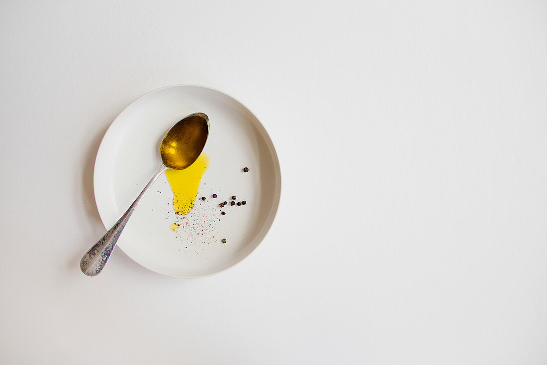 Olivenöl und Pfeffer auf weißem Teller