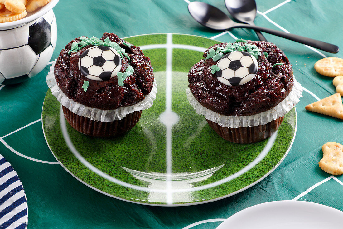 Schokoladenmuffins mit Fußballdekoration auf einem Teller in den Farben eines Fußballfeldes