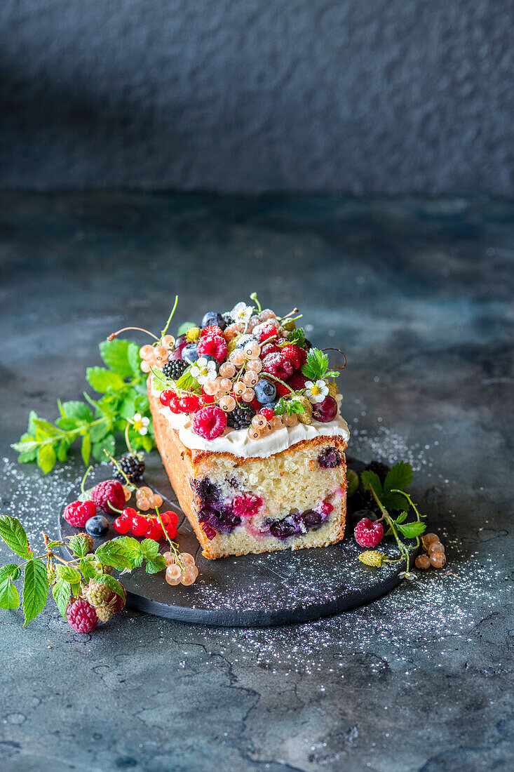 A loaf cake with berries and frosting