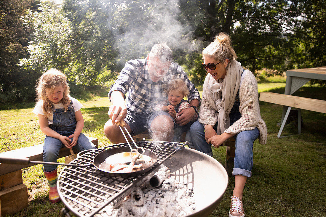 Happy family cooking breakfast on campsite grill