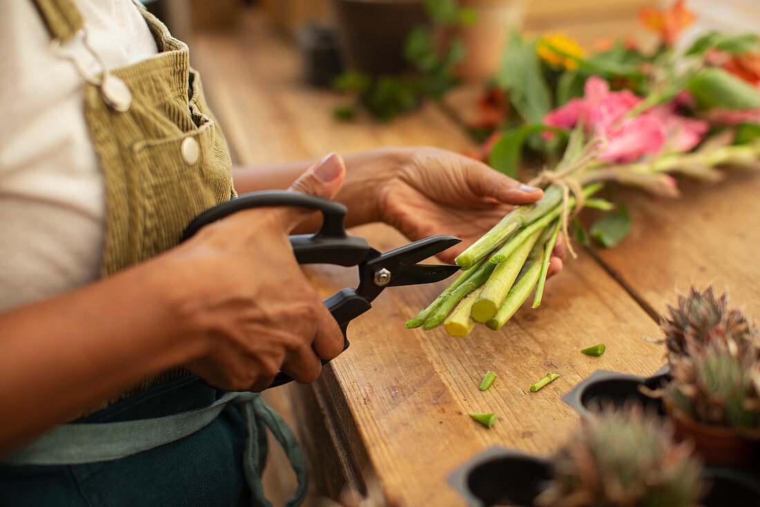 Female florist trimming flower stems with shears