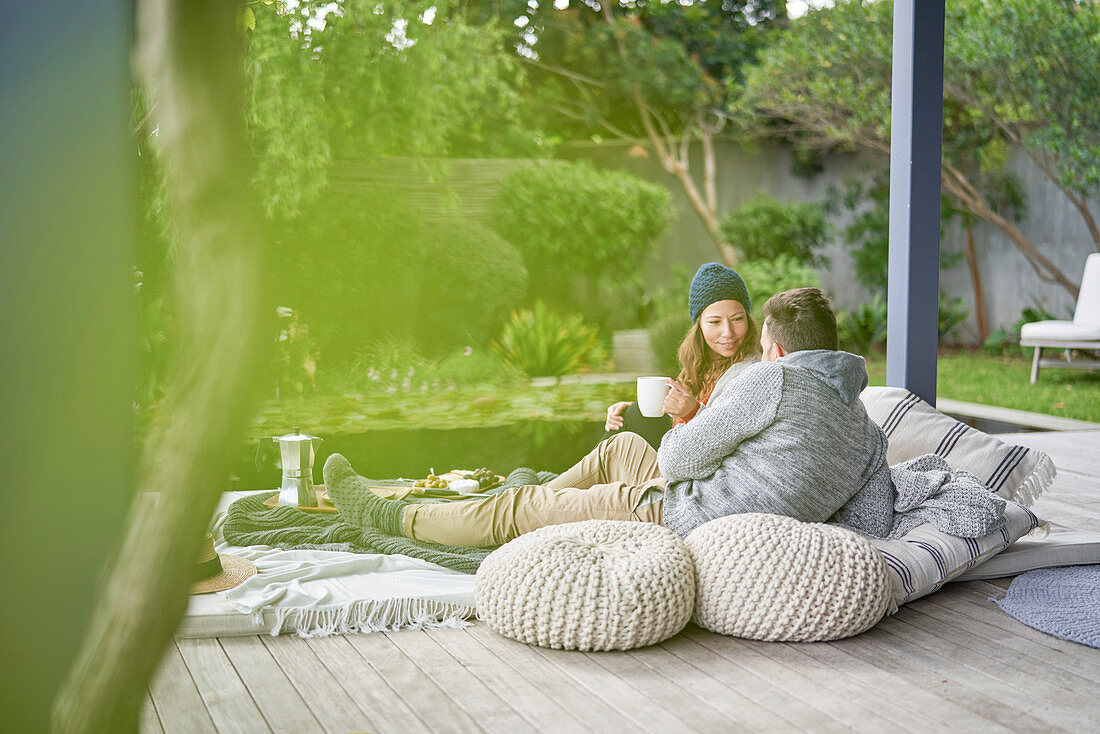 Couple relaxing on cushions with coffee on patio