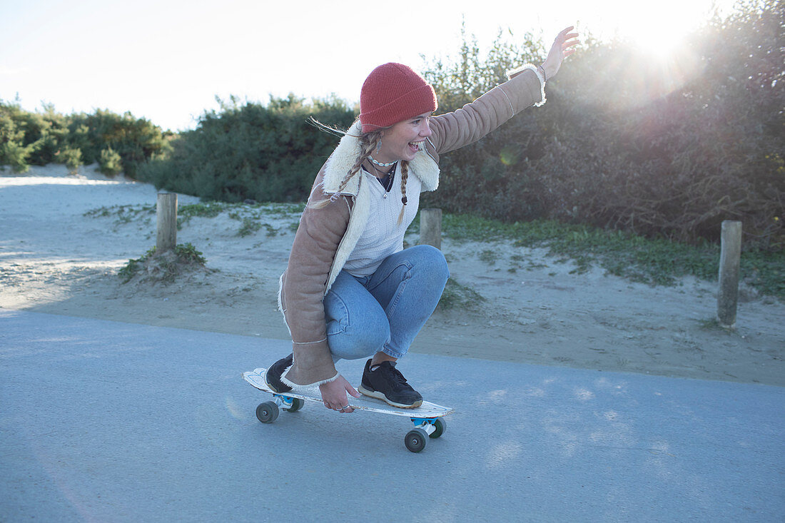 Young woman skateboarding on a beach path