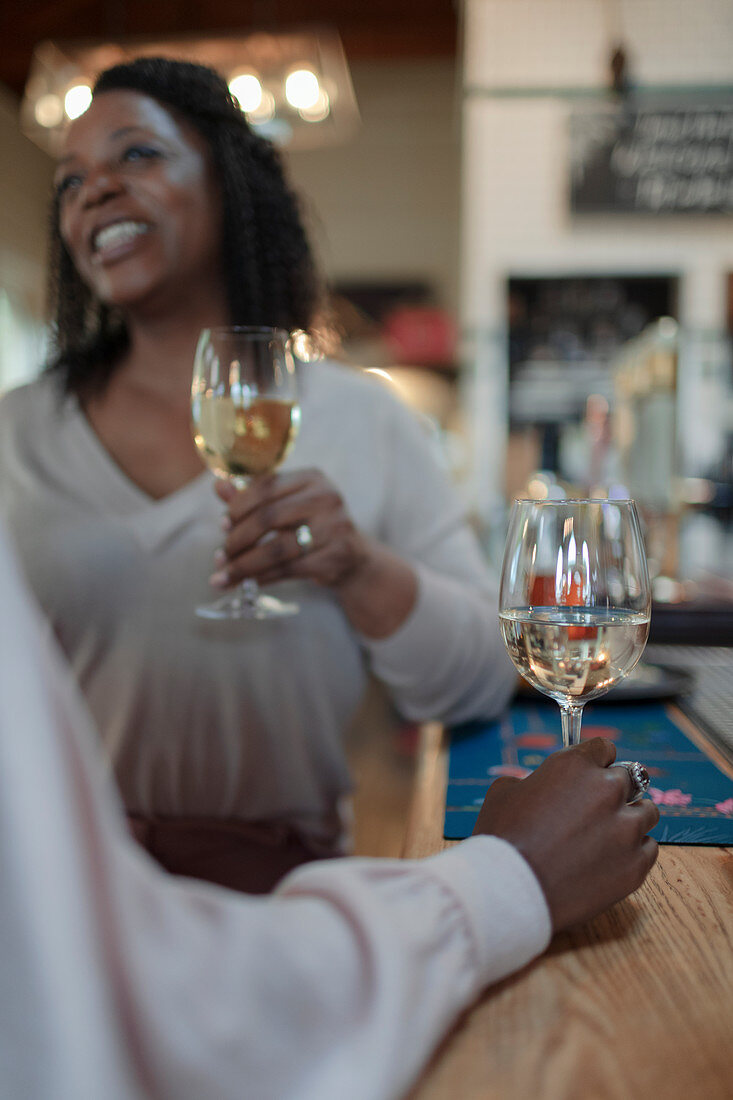 Women friends drinking white wine at bar counter