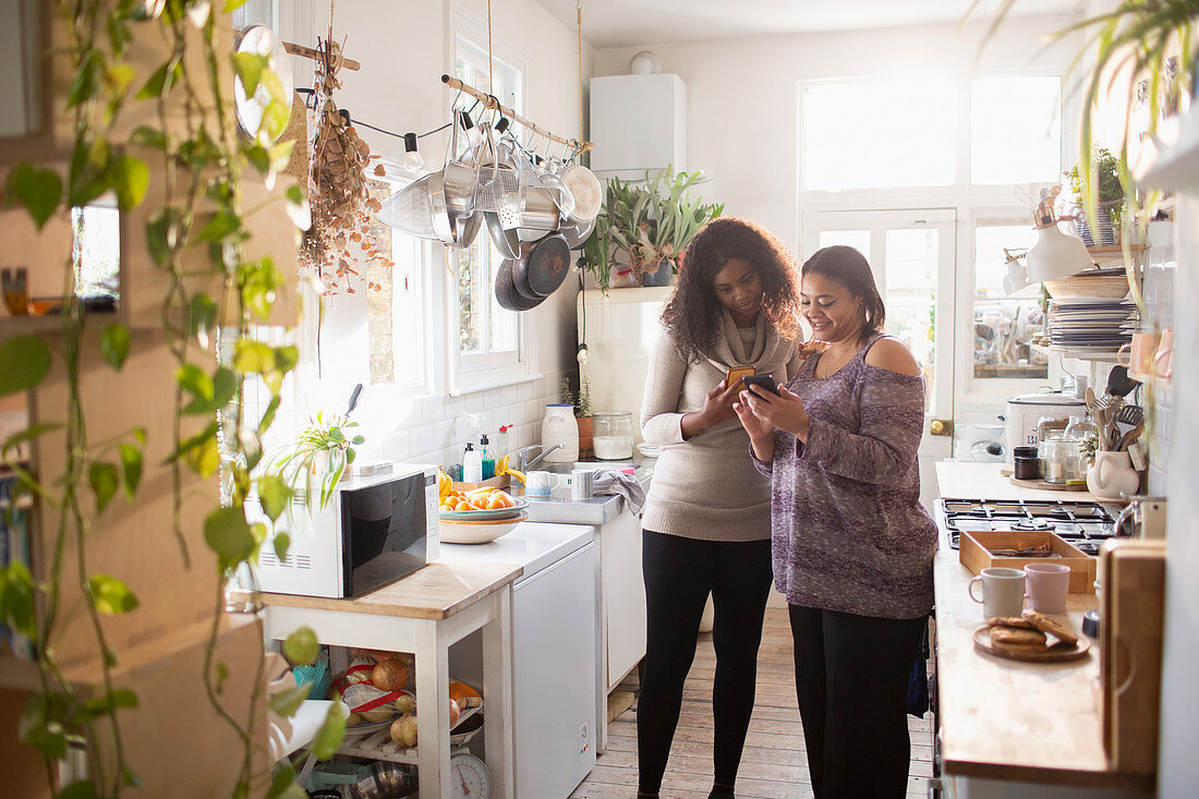 Mother and daughter using smartphone in kitchen