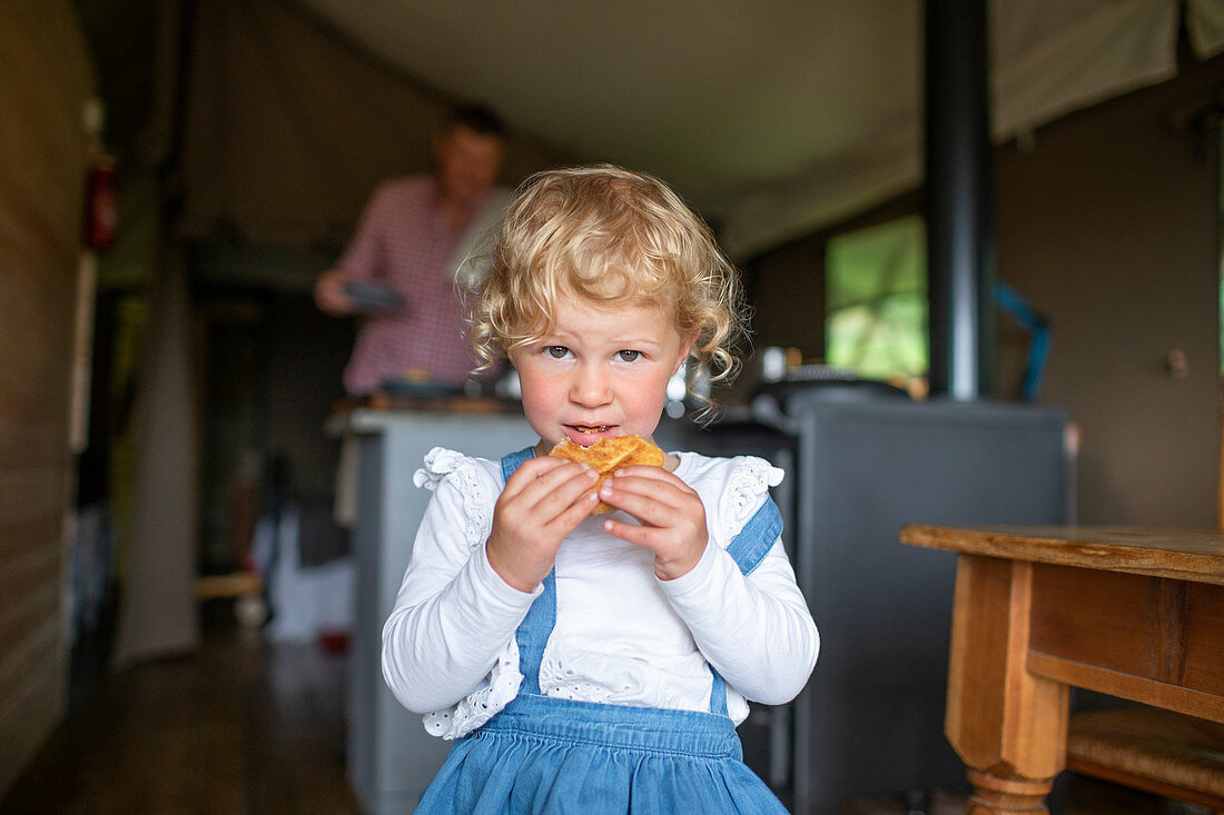 Girl eating biscuit in yurt cabin