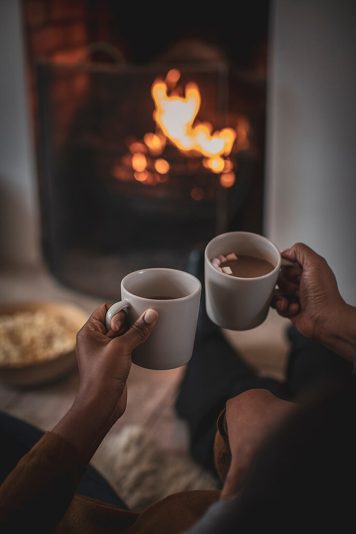 Mother and daughter enjoying hot cocoa by fireplace