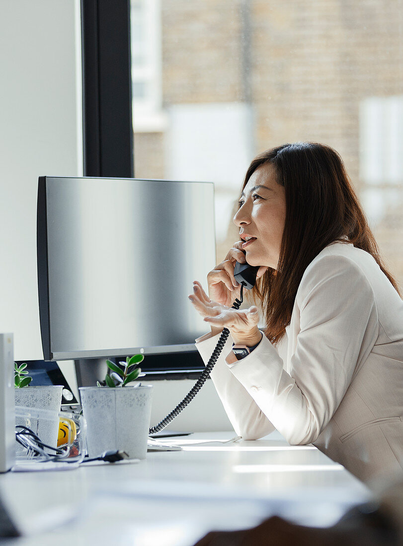 Businesswoman talking on telephone at office window