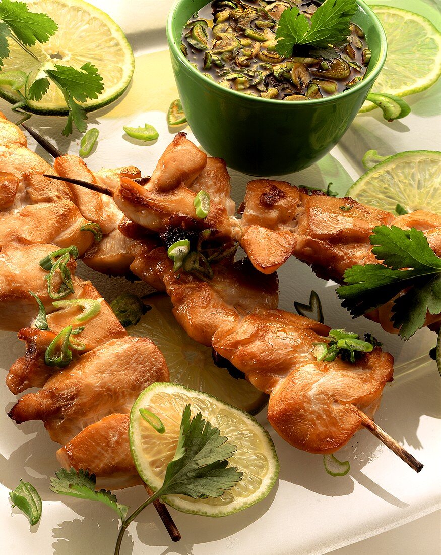 Chicken kebabs, lime slices, and bowl of marinade