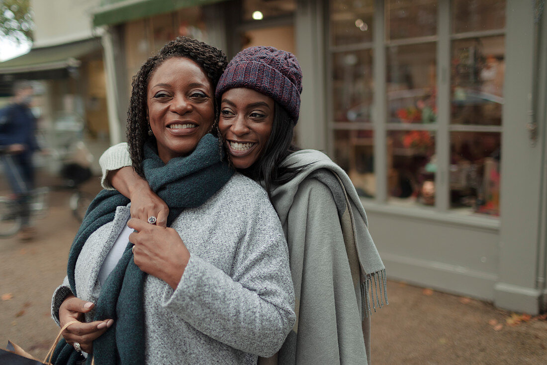 Happy mother and daughter hugging on sidewalk