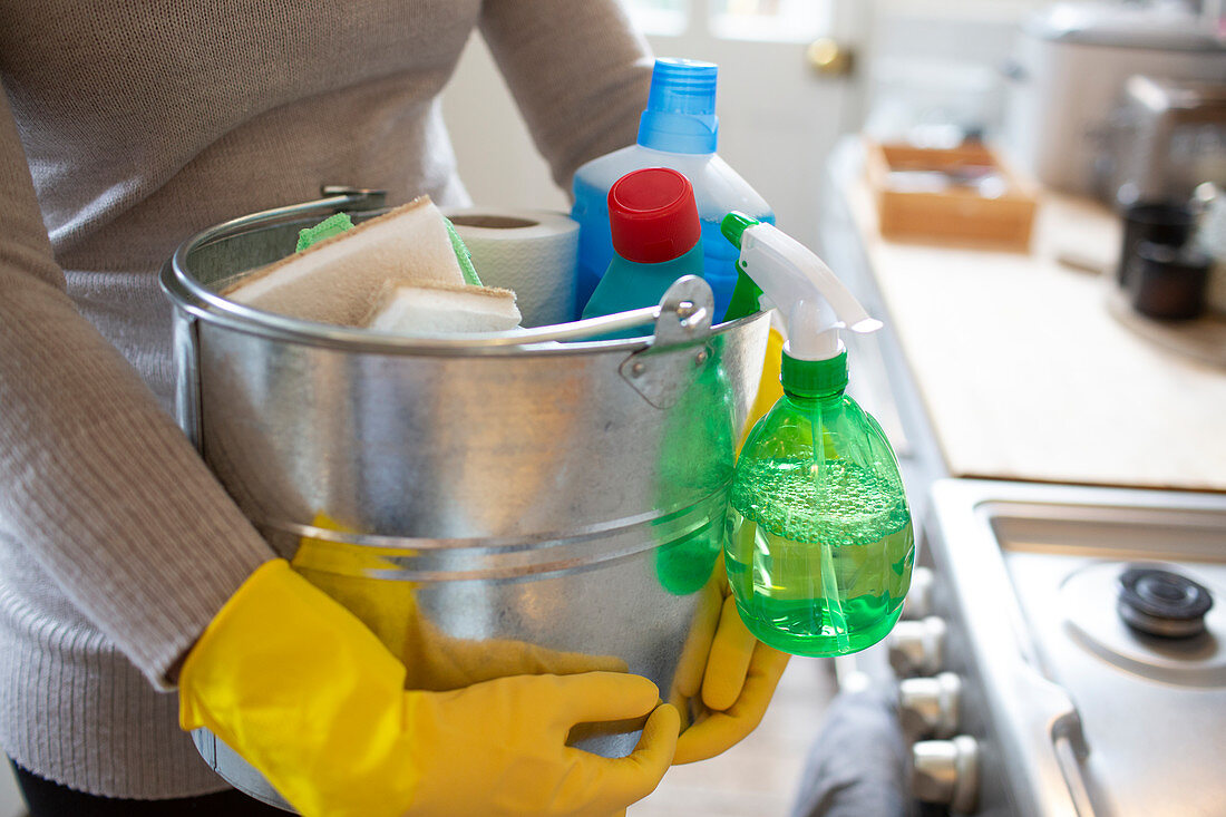 Woman in rubber gloves with cleaning supplies