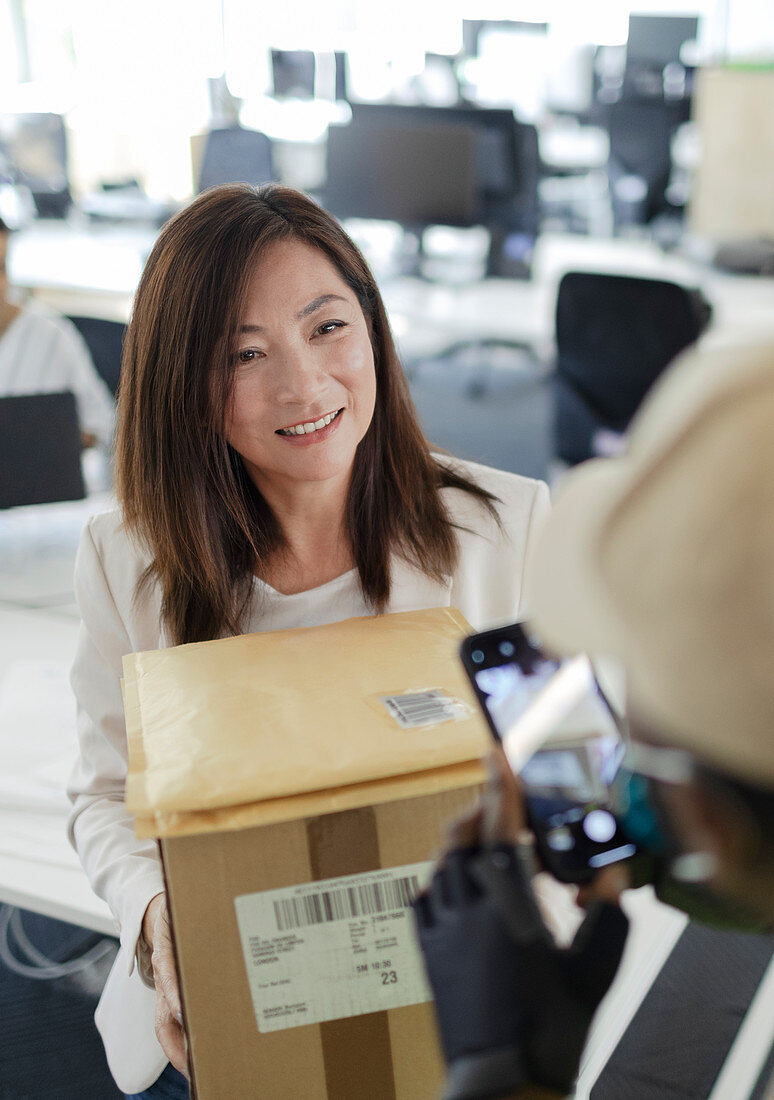 Businesswoman receiving packages from courier in office