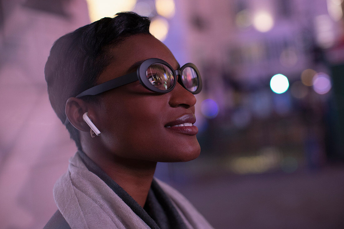 Young woman in eyeglasses on city street at night