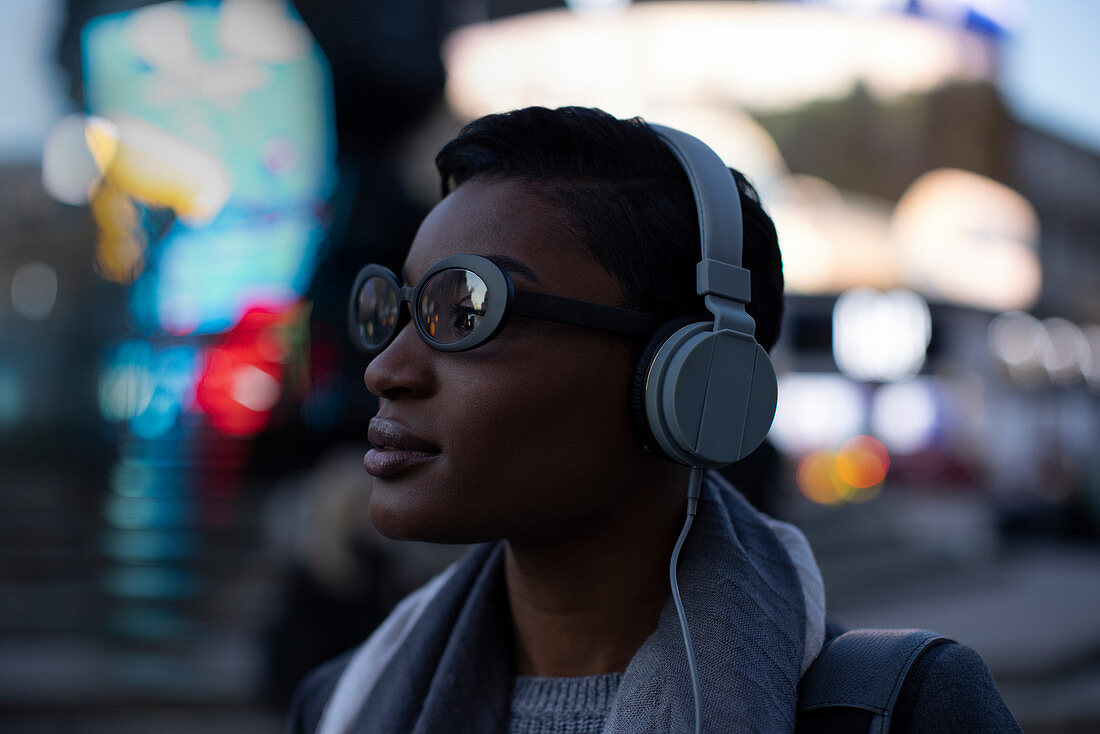 Confident young woman with headphones on urban street