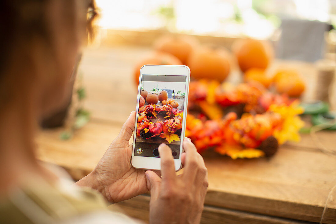 Florist photographing autumn display with a smartphone