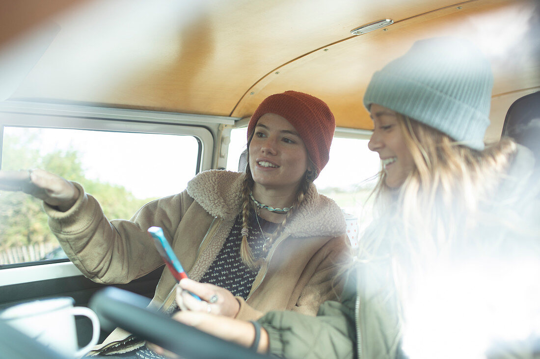 Young women friends using smartphone inside camper van