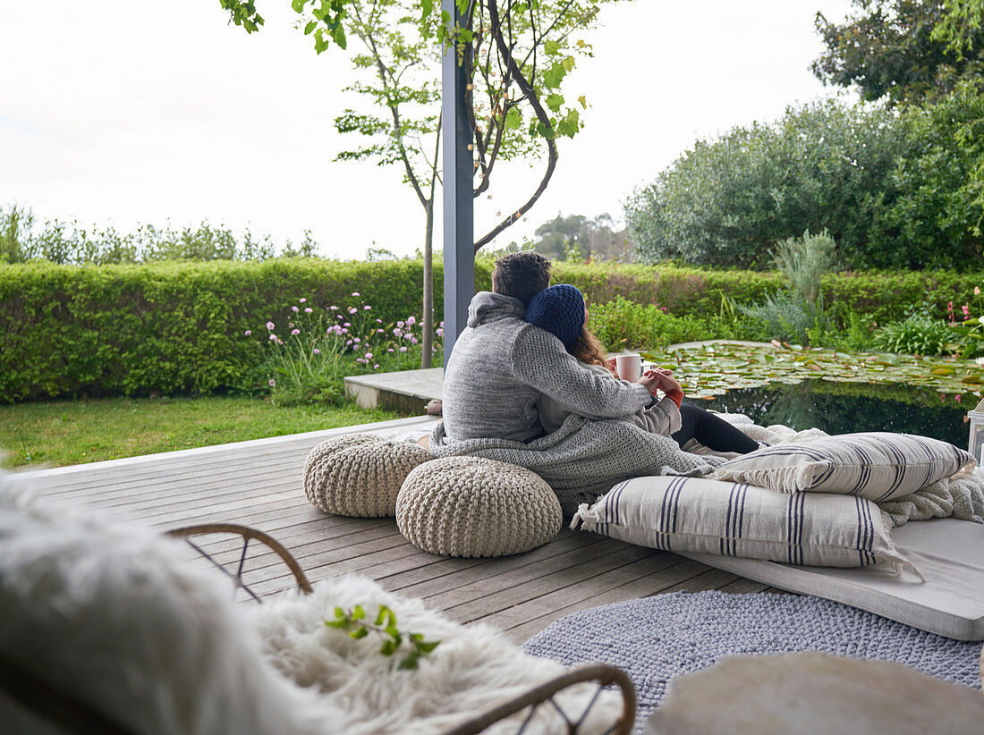 Affectionate couple cuddling on cushions on luxury patio