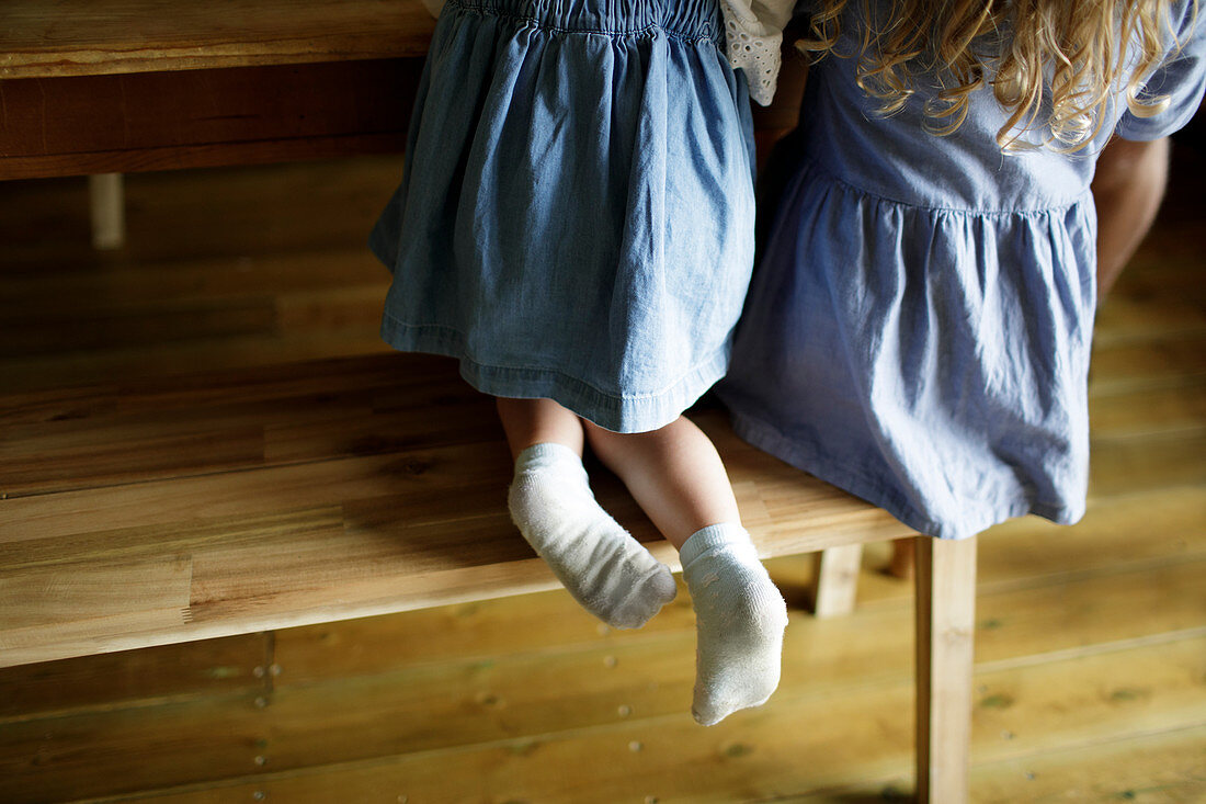 Girl in denim dress with dirty socks at wood dining table