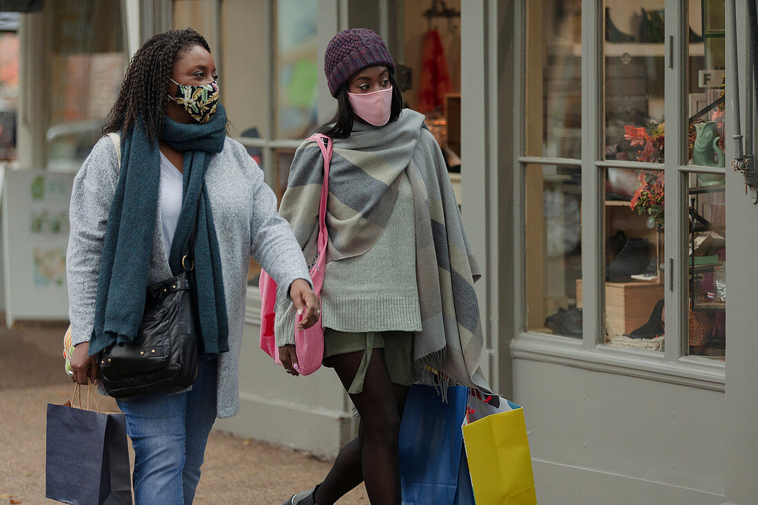 Mother and daughter in face masks with shopping bags