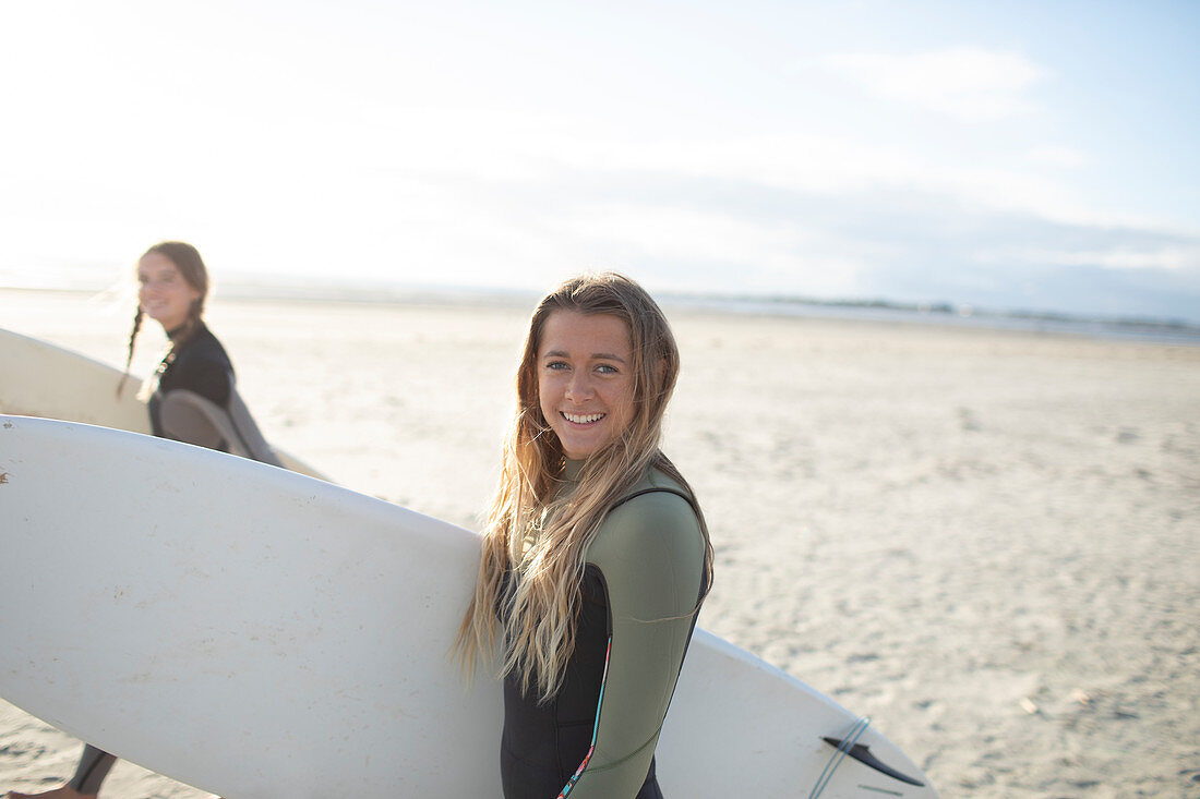 Happy young female surfer with surfboard on sunny beach